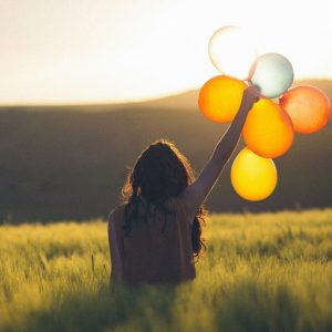 Frau im Feld hält Luftballons